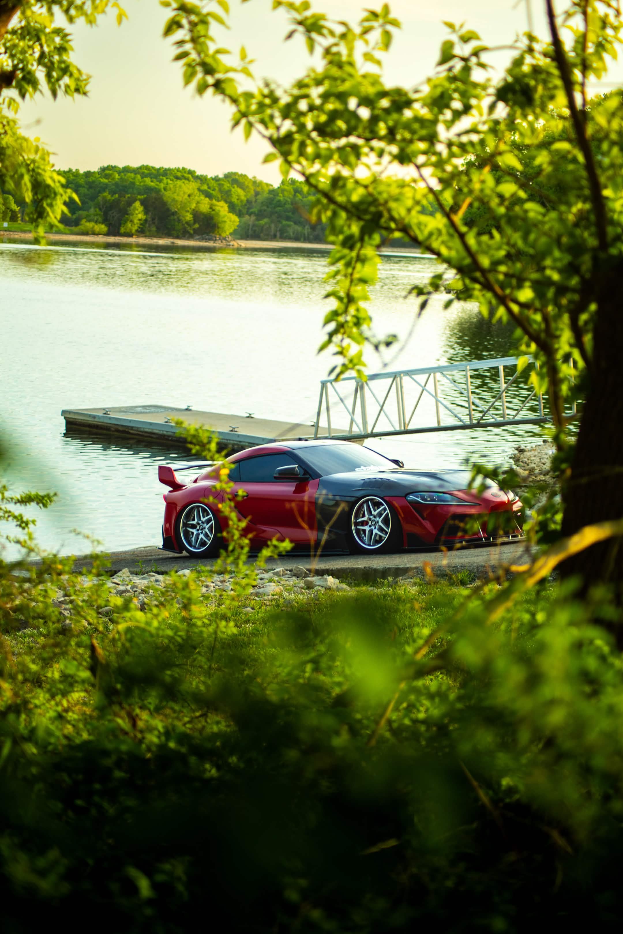 Red MK5 Supra beardedmk5 through trees waterfront